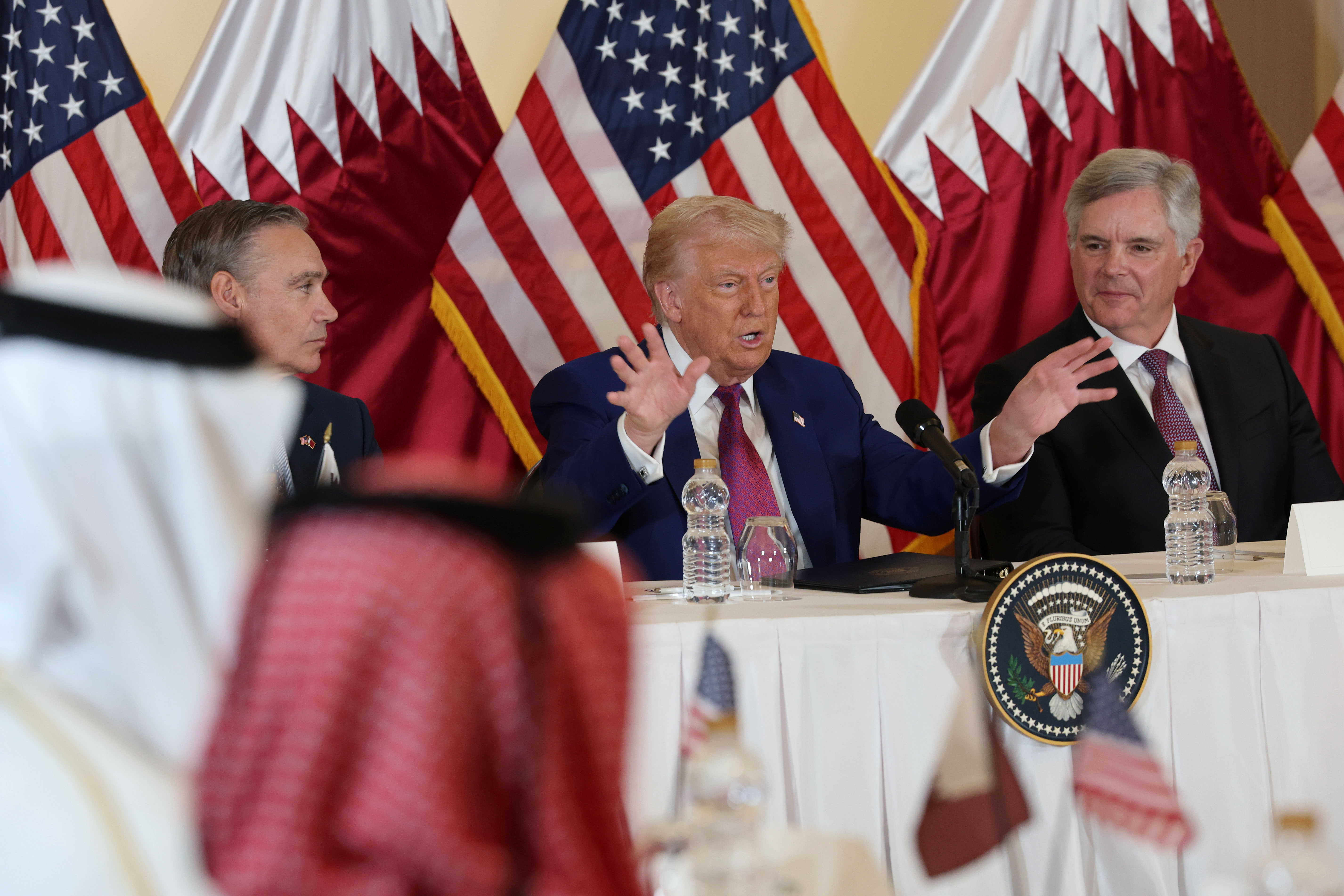 DOHA, QATAR – MAY 15: U.S. President Donald J. Trump, flanked by chairman and CEO of GE Aerospace Larry Culp (R) and CEO of Boeing Kelly Ortberg (L), gestures as he meets with business leaders at the Ritz Carlton Hotel on May 15, 2025, in Doha, Qatar. Trump is on the third day of his visit to the Gulf to underscore the strategic partnership between the United States and Qatar, focusing on regional security and economic collaboration.