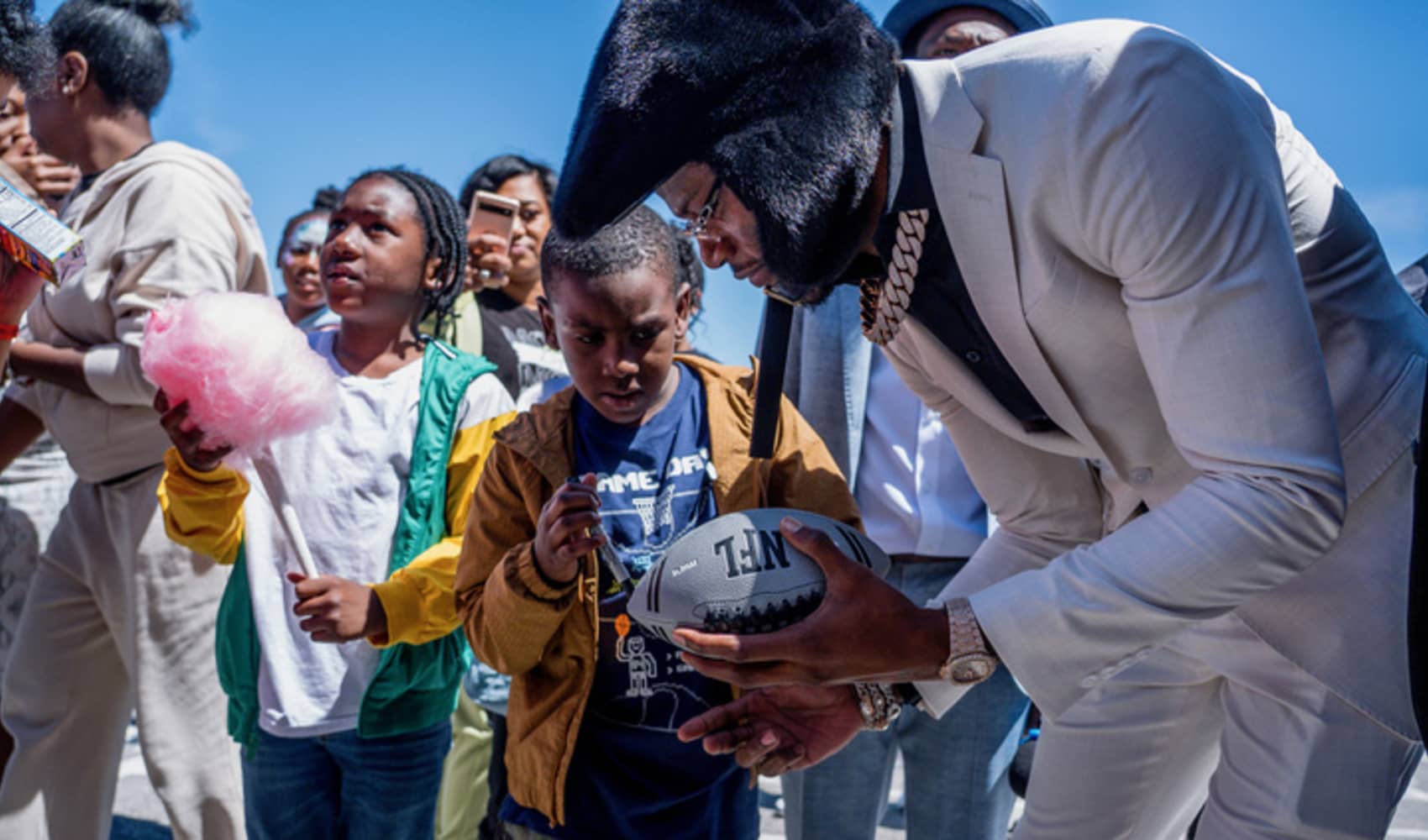 Lamar Jackson signs a football for a young fan.